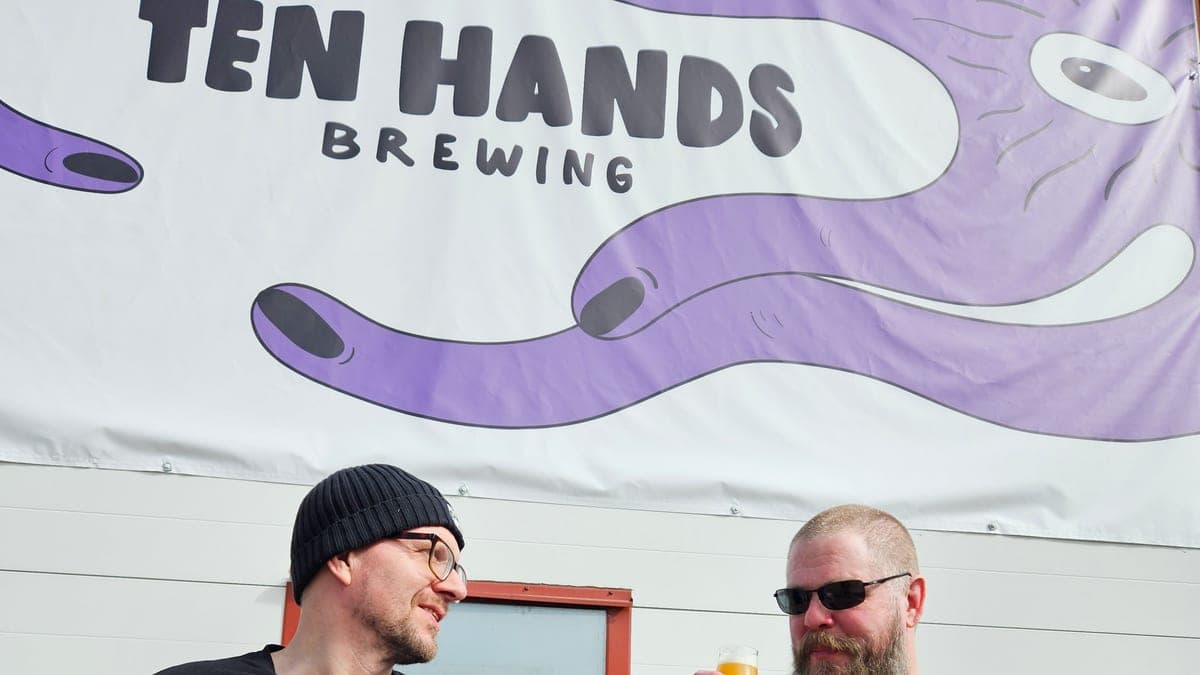 Två av Ten Hands Brewings grundare framför bryggeriets banderoll i Karlstad.